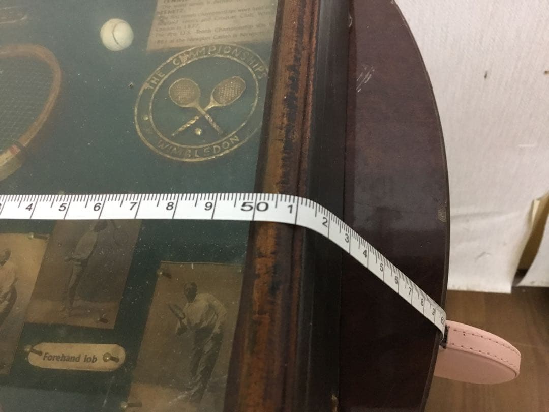 アンティークなテニスラケットの歴史と変遷について解説している彫刻が収められた額装